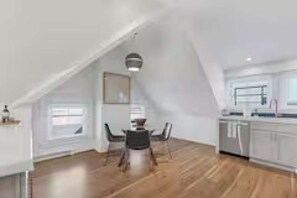 A spacious loft with a high ceiling, a dining area, and a kitchen.