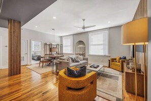A modern living room with a dining area, a sofa, a coffee table, and a lamp.