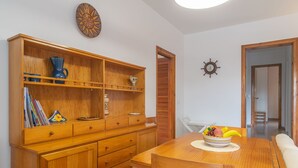 A wooden dining table with a bowl of fruit, a wooden cabinet with various items, and a door leading to another room. - Can Jaume 6 in Es Canutells (Mahón)