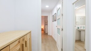 Ein Flur mit Holzausstattung, einer weißen Tür und einem durchgegangenen Tür erkennbaren Badezimmer.