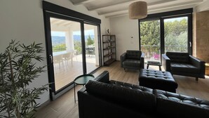 Ein geräumiges Wohnzimmer im modernen Stil, mit einem großen Schiebeglasfenster, das auf einen Balkon mit schöner Aussicht führt.
