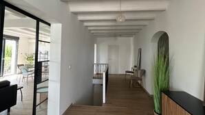 Ein großzügiger Wohnbereich mit Holzboden, einer Glastür zum Balkon und einem Essbereich mit Stühlen und Tisch.