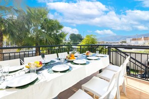 A dining table set outdoors with a view of mountains and palm trees. - Coll Groc in Grau i Platja (Gandia)