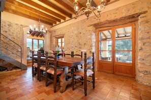 A dining area with a wooden table and chairs, stone walls, and a chandelier. - Son Fuster D Abaix in Alar (Alaro)