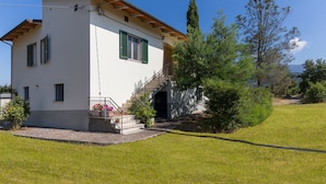 A two-story house with a balcony, a staircase leading to the second floor, and a view of the surrounding greenery and trees. - Countryside House Near To Pratomagno (Terranuova Bracciolini)