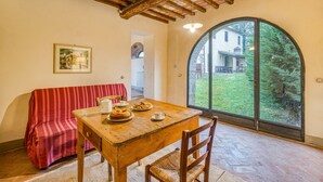 Un comedor con una mesa de madera, sillas y un sofá a rayas rojas.