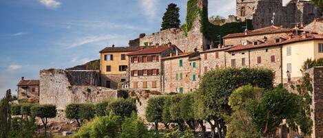 A historic town with stone buildings, a prominent castle, and a paved street.
