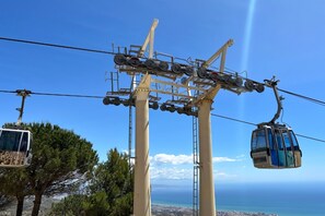 A cable car system with a clear view of the landscape below, including trees and a distant coastline. - La Costa in Benalmadena (Benalmádena)