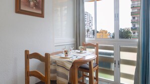 A dining area with a round table, wooden chairs, and a window with a view of buildings.