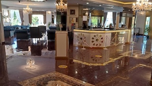 Un vestíbulo amplio con un piso de mármol pulido, un mostrador de recepción y elegantes candelabros.
