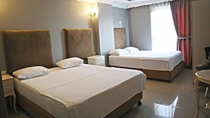 Habitación de hotel con dos camas, una mesita, una silla, una mesita de noche y una lámpara.
