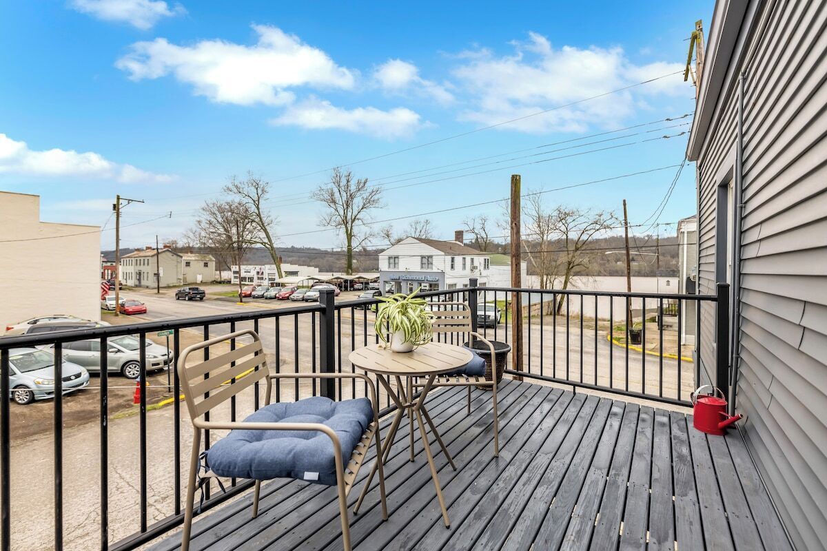 Un balcon avec une table, des chaises et un pot de fleurs.