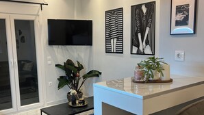 A modern kitchen with a bar area, a flat-screen TV, and decorative wall art. -  High Speed WiFi City Centre Flat (Thessaloniki)