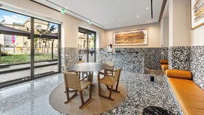 A modern interior with a round table and chairs, a bench, and a large window offering a view of the street. - Hotel Milu Milano (Milan)