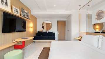 A modern hotel room with a bed, a sofa, a TV, and a mirror.