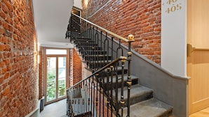 A staircase with black metal railings and wooden steps, leading to a room with a brick wall and a door labeled "405". - Hotel Milu Milano (Milan)