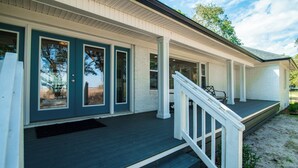 A two-story house with a covered porch and a front door with glass panels. - Cypress Chaos beautiful home with incredible marsh views in Willowbank (Georgetown)