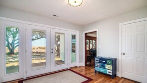 A spacious hallway with wooden flooring, a red and beige rug, and a blue dresser with drawers. - Cypress Chaos beautiful home with incredible marsh views in Willowbank (Georgetown)