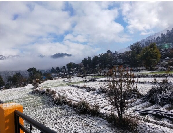 Paisaje nevado con campos en terrazas y una montaña al fondo.