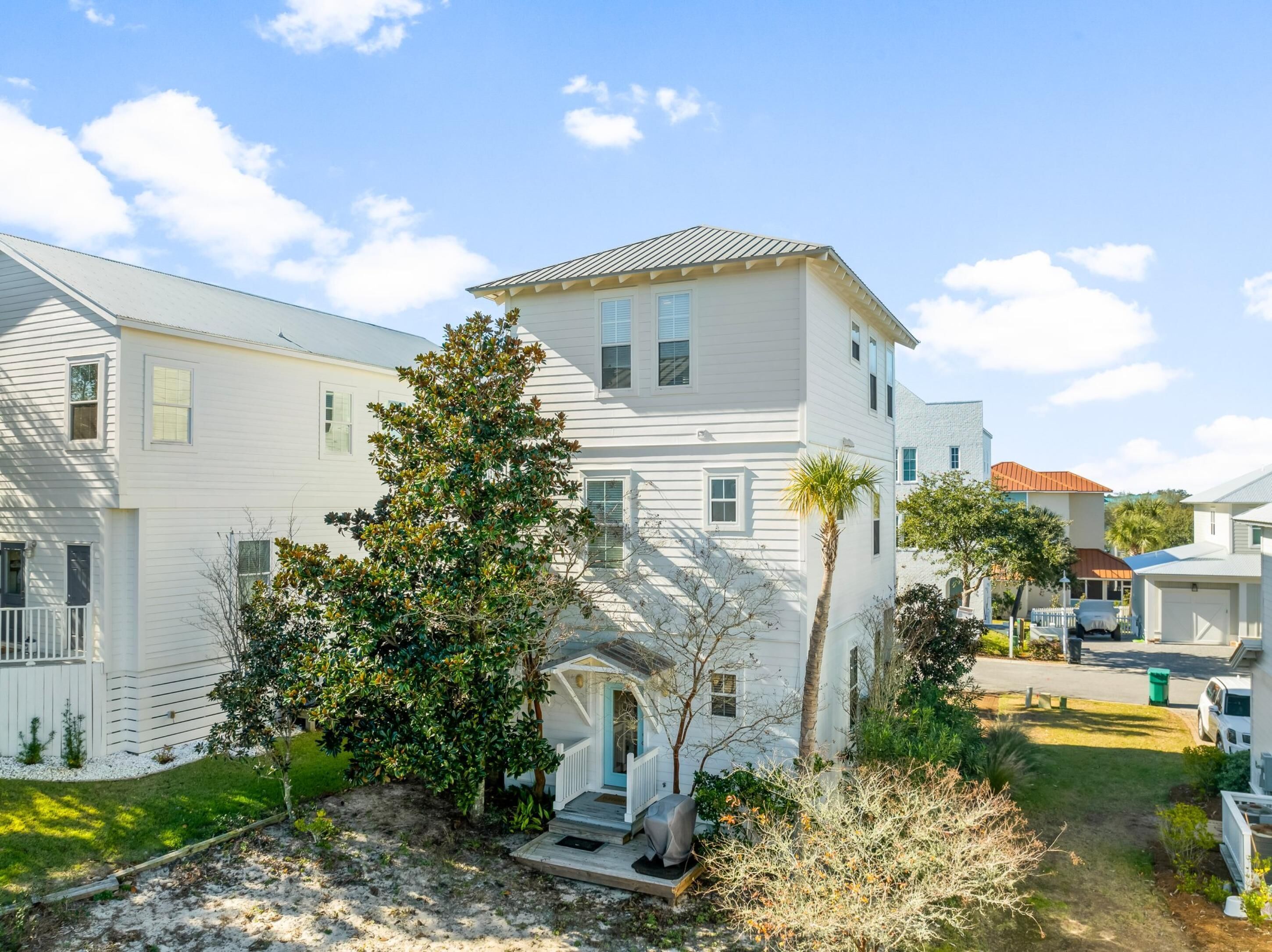 A two-story white house with a front porch, a small garden, and a clear blue sky.