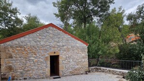 Un bâtiment en pierre avec un toit rouge, une cour pavée et une clôture en métal.