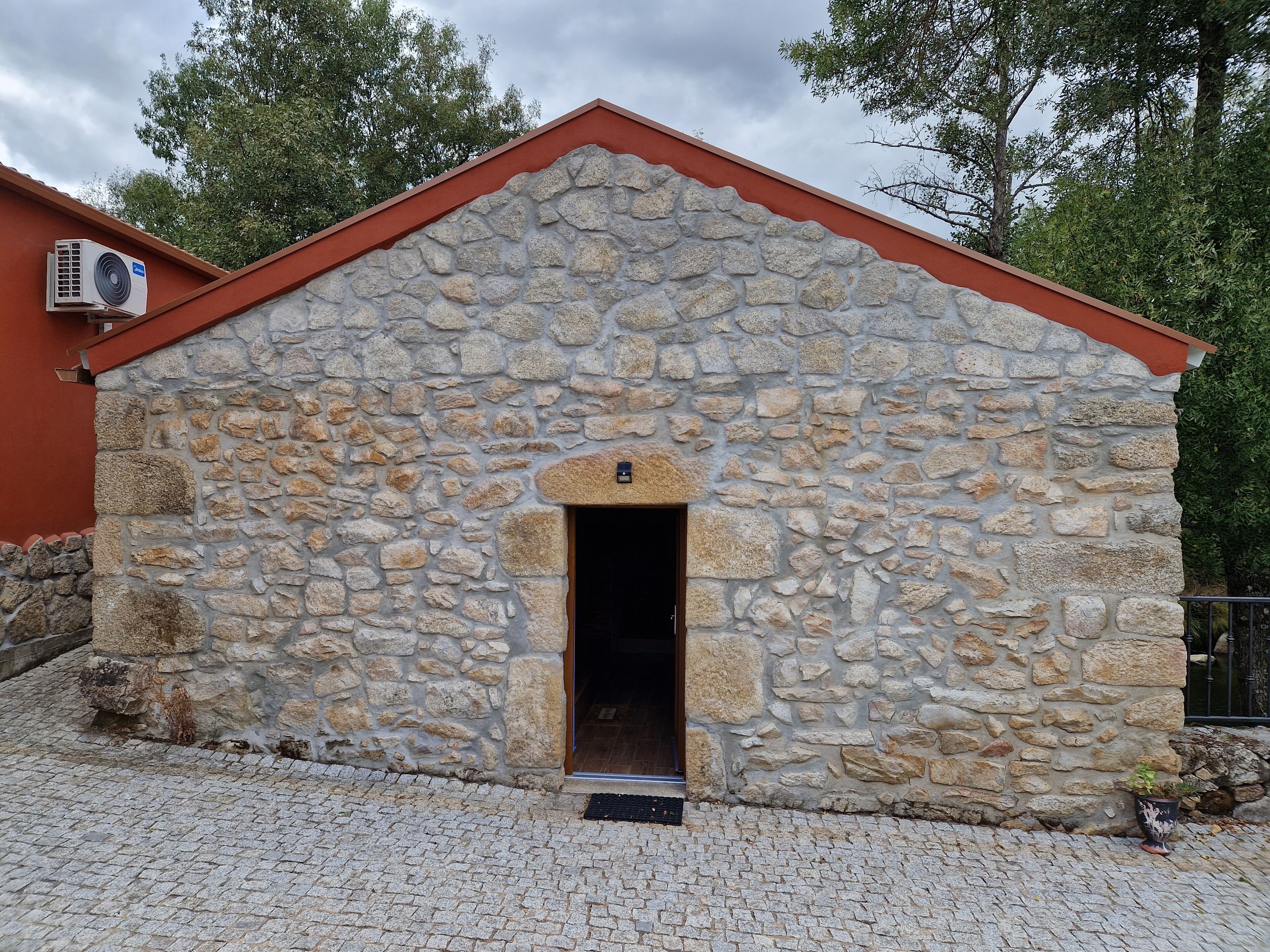A stone building with a red roof and a small entrance.