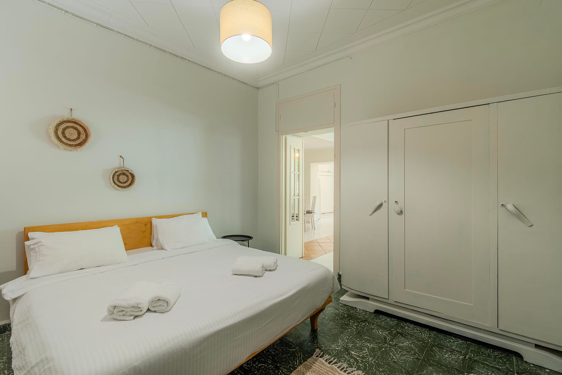 A bedroom with a bed, a wardrobe, and a door leading to another room.