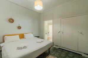 A bedroom with a bed, a wardrobe, and a door leading to another room. - Joyful Secret Garden Residence Downtown, House (Chania)