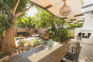 Un patio al aire libre con una mesa de madera, sillas, un columpio y una lámpara colgante.