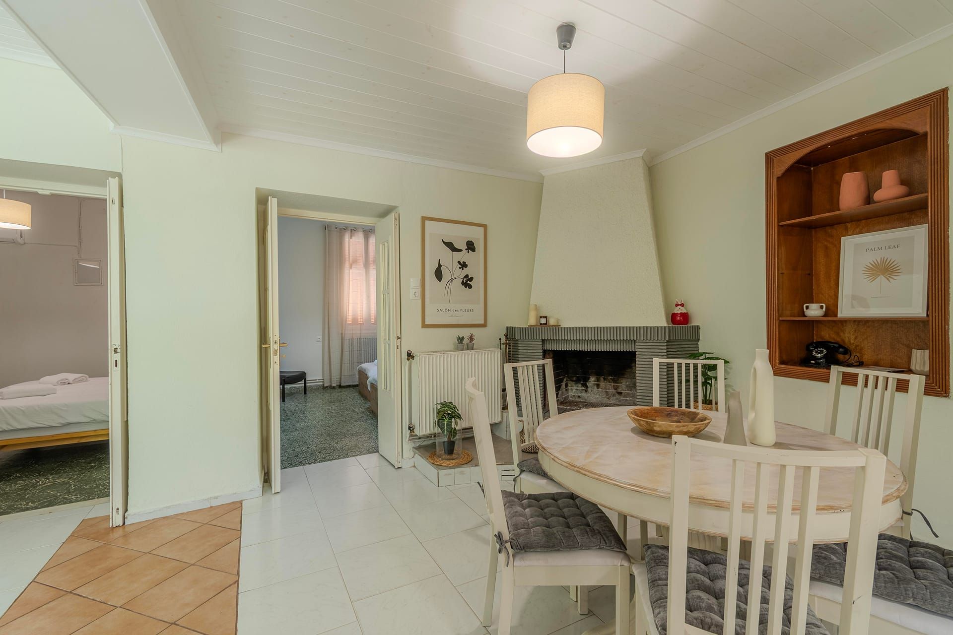 Un coin repas avec une table ronde, des chaises blanches et un luminaire suspendu.