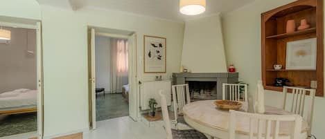 Un coin repas avec une table ronde, des chaises blanches et un luminaire suspendu.