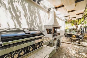 Un espacio al aire libre con una parrilla, una chimenea, una mesa y sillas.