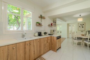 Een moderne keuken met een groot kookeiland, houten kastjes en uitzicht op groen.