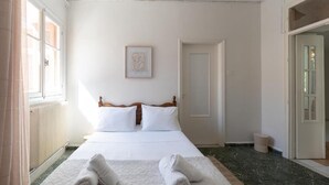 A bedroom with a bed, a framed picture on the wall, and a window with curtains. - Joyful Secret Garden House by 8essentially (Chania)