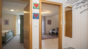 Un couloir avec des portes en bois, un lit et un coin repas comprenant une table et des chaises.
