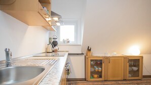 Een moderne keuken met een grote spoelbak, een koffiezetapparaat en een kast met servies.