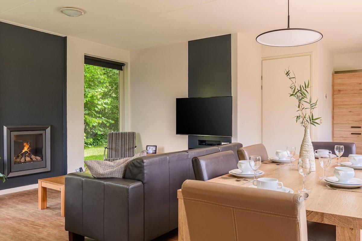 A modern living room with a fireplace, a television, and a dining area set for a meal.