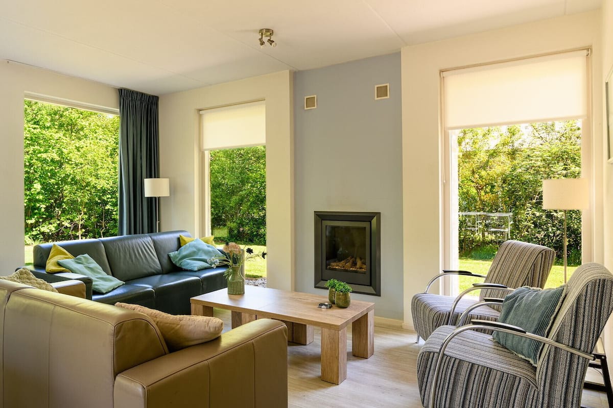 A modern living room with a sofa, armchair, and a fireplace.