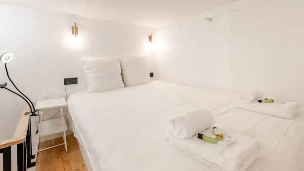 A modern hotel room with a large bed, bedside tables, and a desk with a lamp. - Stylish Duplex in Vibrant Central Paris (Paris)