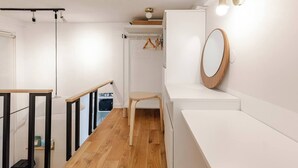 A modern, minimalist bathroom with white walls, a wooden floor, a large mirror, and a hanging light fixture. - Stylish Duplex in Vibrant Central Paris (Paris)
