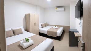 A hotel room with two beds, a wardrobe, a television, and a desk with a computer. - Hostal Tamaca (Santa Marta)