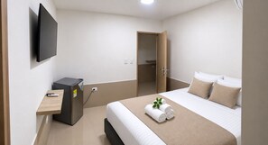 Ein Hotelzimmer mit Bett, Schreibtisch, Fernseher und Kleiderschrank.