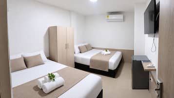 Habitación de hotel con dos camas, un armario, un televisor y un escritorio con una computadora.