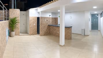 A clean, modern reception area with a reception desk, a small seating area, and a potted plant.