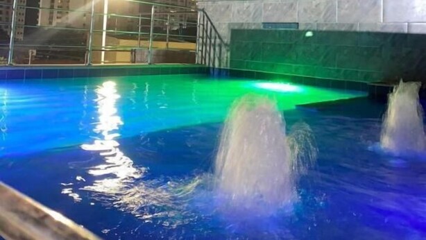 En inomhuspool med fontäner och en stadsbild i bakgrunden.
