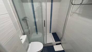 A modern bathroom with a glass-enclosed shower, a toilet, and a towel rack.