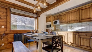 A wooden interior with a dining table set for four, a bench, and a window with a view of trees. - Cosy 74m2 View Garden | SkiLift 250m | Parking Bus (Chamonix-Mont-Blanc)