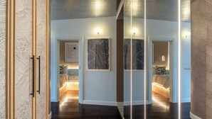 A modern interior with a dark wood floor, white walls, and a glass partition. There are framed artworks on the walls and a bed with a headboard in the room. - Lion Apartments - Apartment in Old Town (Gdansk)