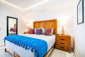 Une chambre d’hôtel avec un grand lit, une tête de lit en bois, une table de chevet avec une lampe et un miroir au mur.