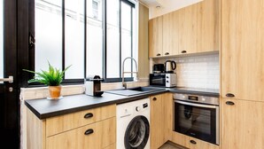 A modern kitchen with wooden cabinets, a built-in washing machine, a coffee maker, and a toaster.